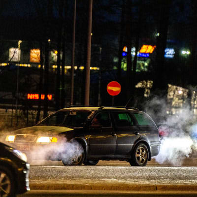 Bilavgaser i nattlig stad