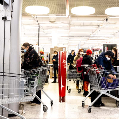 Ihmisiä kauppakeskuksessa ruokakaupan kassalla.