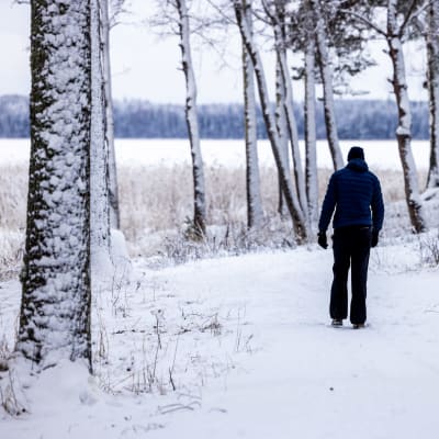 Henkilö kävelee lumisessa maisemassa.