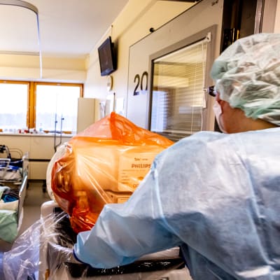 En skötare som ska ta en röntgenbild på en coronapatients lungor.