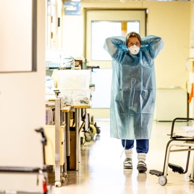 En sjukskötare klär på sig skyddsutrustning inför arbete med coronapatienter.