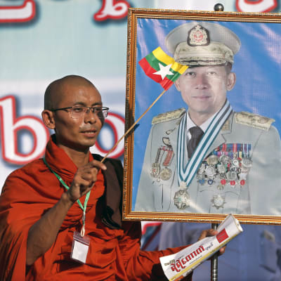 En buddhistisk munk viftade med en flagga och ett porträtt av överbefälhavare Min Aung Hlaing under en demonstration till stöd för militären i Rangoon den 14 oktober 2018.