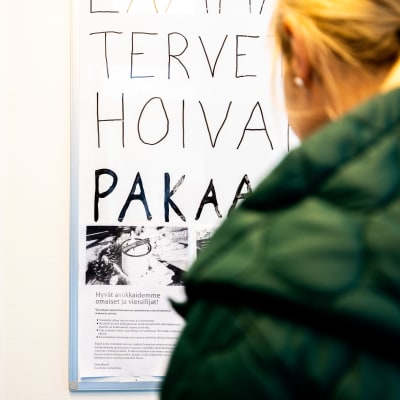 Vierailija lukee hoivakodin ohjeita vierailijoille ennen vierailua vanhusten hoivakotiin.