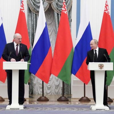 Aleksandr Lukasjenko och Vladimit Putin står vid respektive podium och håller presskonferens framför en rad av belarusiska och ryska flaggor.