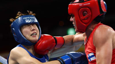 Mira Potkonen i röd tröja delar ut ett slag mot en motståndare i blått.