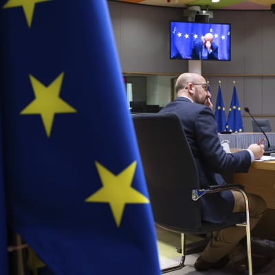Europeiska rådets ordförande Charles Michel. Bilden domineras av en stor EU-flagga i förgrunden. I bakgrunden syns en videoskärm.