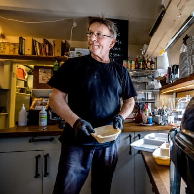 En man lagar take away portioner i ett café