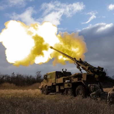 En haubits, det vill säga en slags modern kanon, avfyrar ett skott i Ukraina på ett fält.