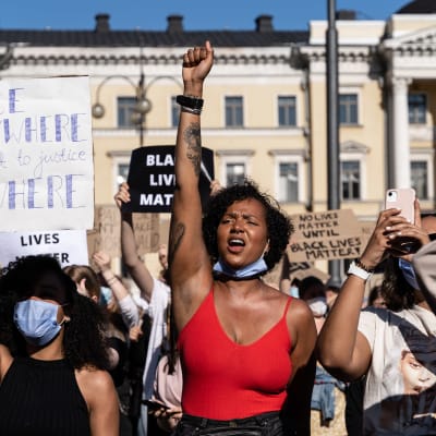 En kvinna i röd topp håller upp knytnäven under Black Lives Matter-demonstrationen.