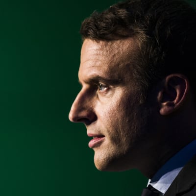 Emmanuel Macron i profil mot svart bakgrund.