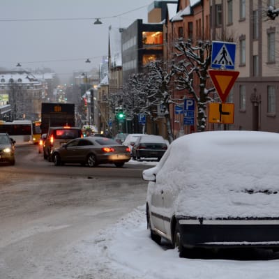 Trafik och en snöig bil i Puolalabacken i Åbo