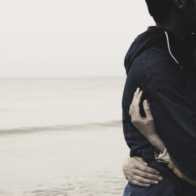 Ett par kramar varandra på stranden.