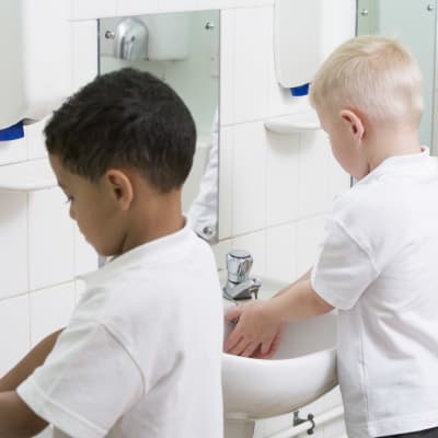 Tre barn står vid varsin lavoar och tvättar sina händer.