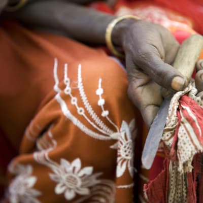 En kvinna håller en kniv som hon tidigare använde vid könsstympning i Etiopien.