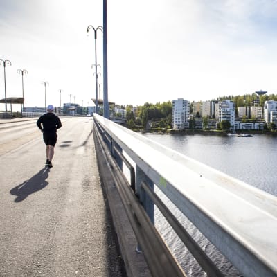 Juoksija Kuokkalan sillalla ja oikealla puolella Kuokkalan kerrostaloja Jyväsjärven rannalla.