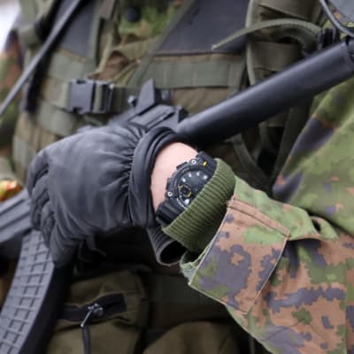 Närbild av en person i militäruniform som håller i ett vapen.