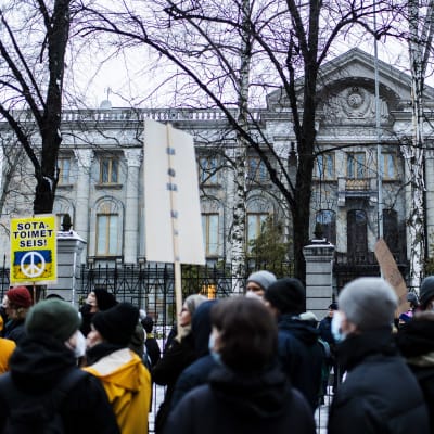 En folkmassa demonstrerar med plakat utanför Rysslands ambassad i Helsingfors.