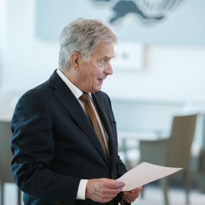 Sauli Niinistö håller ett pappersark i handen.