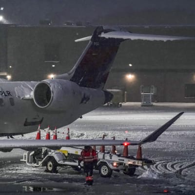 Lentokenttätyöntekijä kävelee kiitotien läpi lumimyrskyn aikana.