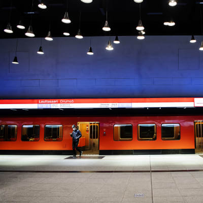 Henkilö astuu ulos metrosta Lauttasaaren metroasemalla.