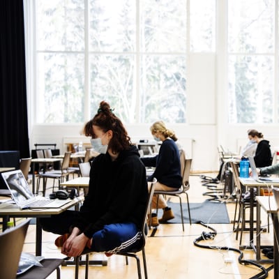 Studentskrivningar i ett gymnasium i Helsingfors i mars 2021. De studerande bär munskydd.