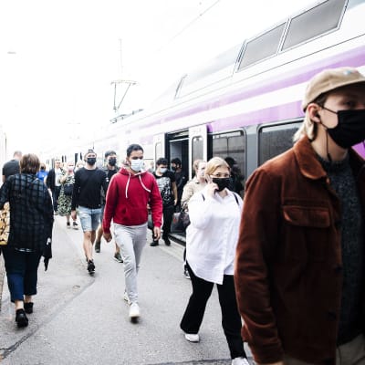 Många människor med munskydd på Helsingfors järnvägsstation.