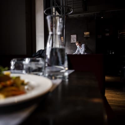 En matportion, och i bakgrunden en servitör som jobbar på restaurang Vltava i Helsingfors i oktober 2020.