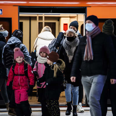 Personer i munskydd stiger av metron. 