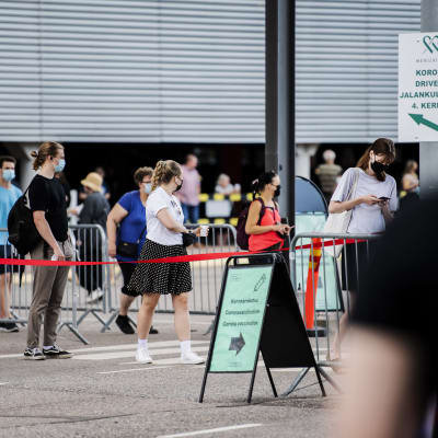 Personer köar utanför mässcentret i Helsingfors för att bli vaccinerade. 