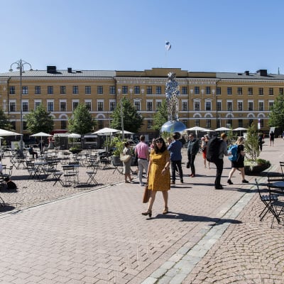 Personer på kaserntorget i Helsingfors och uteservering med koronasäkra avstånd. 