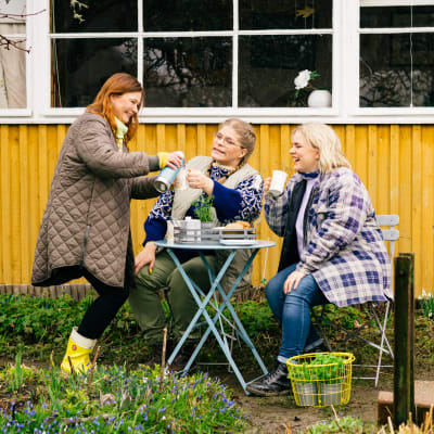 Kädet multaan -ohjelman juontajat Taina Suonio, Enni Koistinen ja Inkeri Alatalo kahvittelevat ulkona.