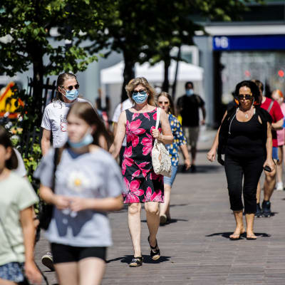 Människor går på stan i Helsingfors i juni 2021. Många av dem bär munskydd.