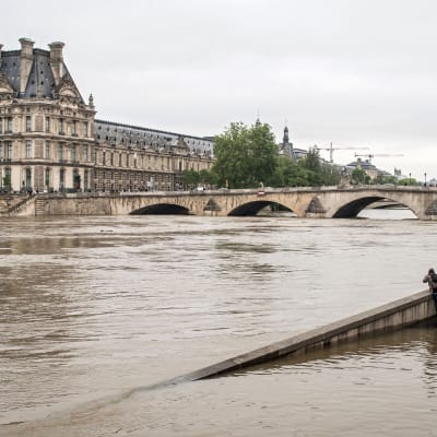 Seinejoki, jossa pinta noussut, joen takana Louvren taidemuseo. Etualalla joitakin ihmisiä katselemassa ja ottamassa kuvaa.