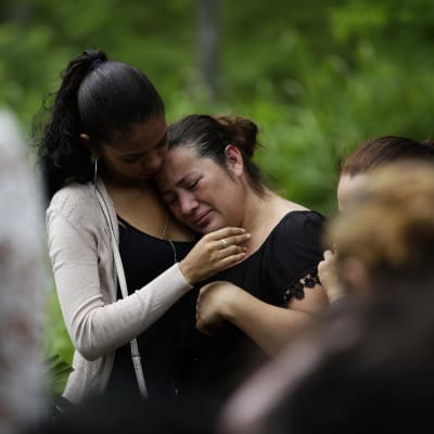 nainen itkee hautajaisissa, joissa audataan nuorta opiskelijaa