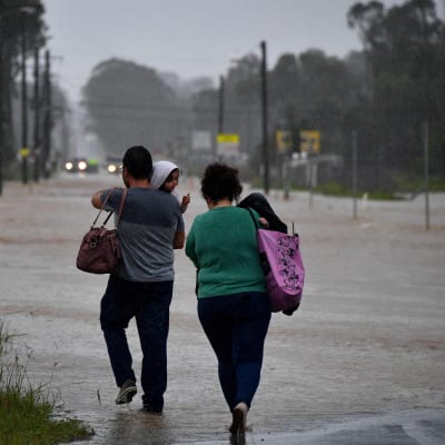 Invånare traskar genom en översvämmad väg under kraftigt regn i västra Sydney den 20 mars 2021.