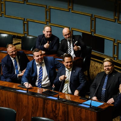 Jani Mäkelä, Mauri Peltokangas, Sanna Antikainen, Petri Huru, Mikko Lunden, Vilhelm Junnila ja Jari Ronkainen poseeravaat keskustelun loputtua kuvaa varten eduskunnassa 17. toukokuuta.