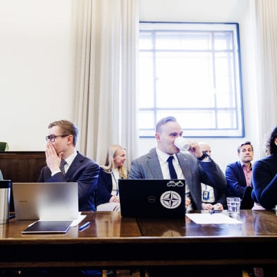 Jenni Pitko, Oras Tynkkynen, Atte Harjanne och Fatim Diarra sitter bredvid varandra vid ett mörkt bord. Jenni Pitko och Oras Tynkkynen pratar med varandra.