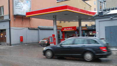 En bil kör förbi en bensinstation.
