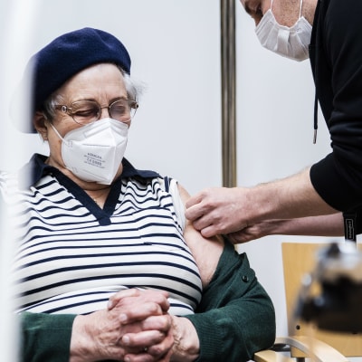 En äldre kvinna får en spruta i armen.