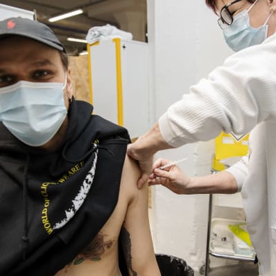 Ung person får coronavaccin i armen. Sjukskötaren Tiina Palm vaccinerar astmatikern Juha Sjögren.