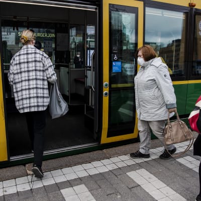 Personer stiger ombord på en spårvagn i Helsingfors centrum den 14 april 2021.