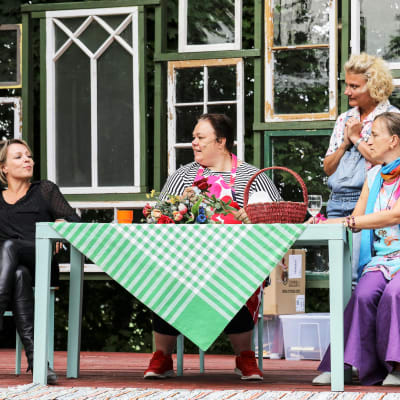 Grupp kvinnor sitter runt ett bord.
