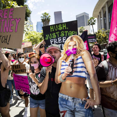 Mielenosoittajia kadulla kyltteineen, mukana myös iso pahvikuva Britney Spearsista
