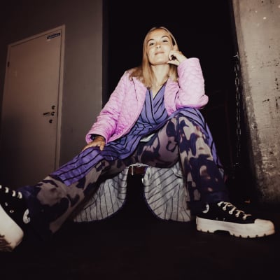 Emilia Hernesniemi istuu työnnettävän kärryn päällä katsoen kameraan.