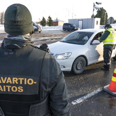 Två gränsbevakare checkar en personbil vid ett gränsövergångsställe.