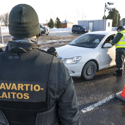 Gränsbevakare i tjocka overaller granskar en personbil på gränsen mellan Sverige och Finland i Torneå och Haparanda.