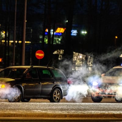 Bilavgaser i nattlig stad