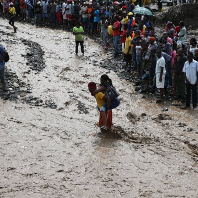 Människor försöker ta sig över floden La Digue i sydvästra Haiti.