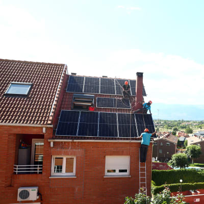 Aurinkopaneeleja asennetaan asuintalon katolle.