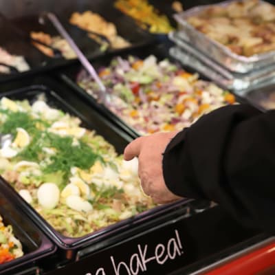 Asiakas ostamassa salaattia kaupan myyntipisteestä